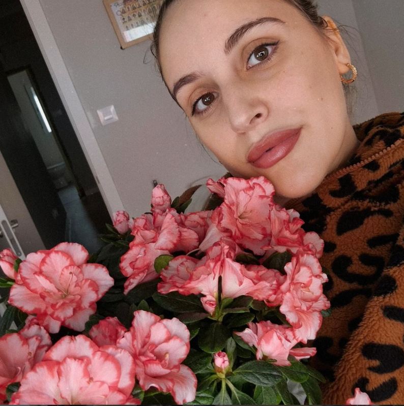 Naiara, creadora de Aloumiño, sonriendo junto a unas flores rosas